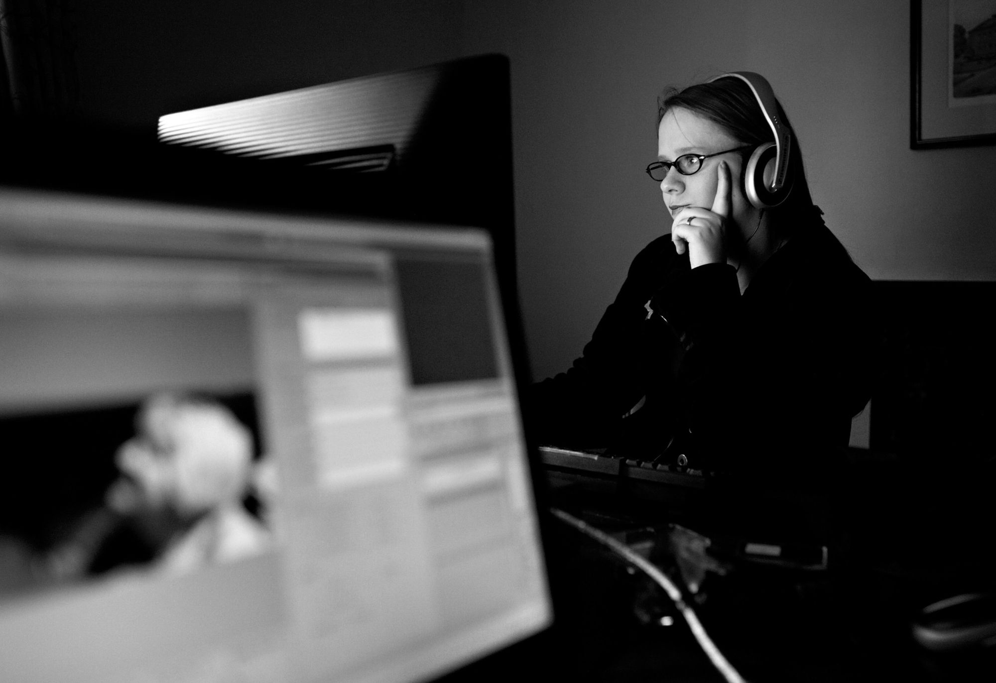 Sylvia Broeckx at her editing desk, wearing headphones and watching the screen
